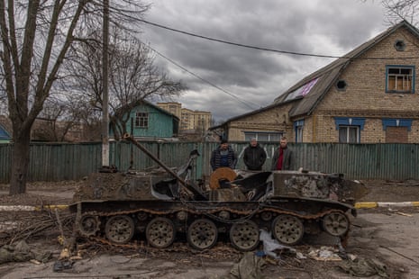 Two men look at a destroyed Russian military vehicle on the street in Bucha, a town retaken by the Ukrainian army, northwest of Kyiv.