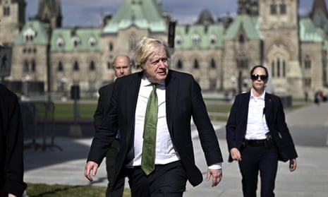 Boris Johnson walks along a street with security guards in the background