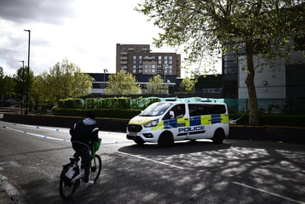 A police van parked across a road that is closed off with police tape.