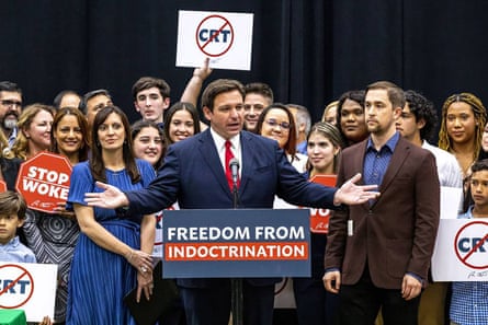 Ron DeSantis speaking above a sign that says ‘freedom from indoctrination’