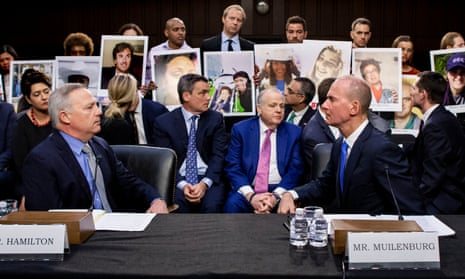Dennis Muilenburg, right, and vice-president and chief engineer John Hamilton sit in front of people holding pictures of loved ones during a US congressional hearing.