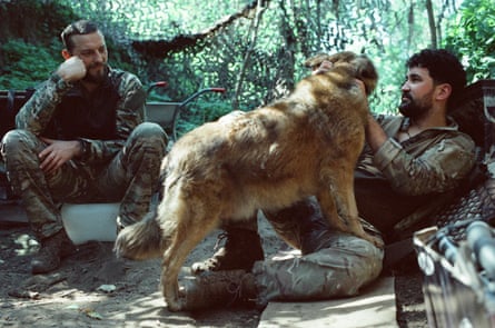 Young and Dzhango sit on the ground, one petting a dog.