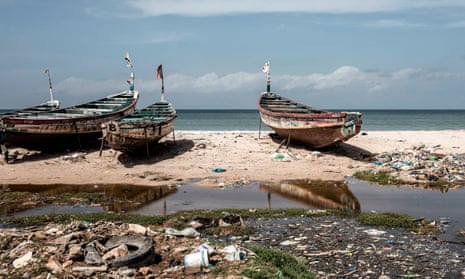 Fishing boats on a beach with rubbish on it in Africa