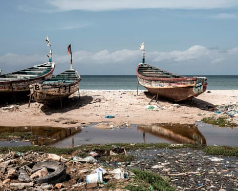 Fishing boats on a beach with rubbish on it in Africa