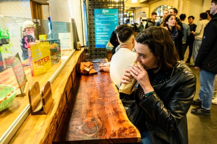 A woman eats a flatbread at a counter.