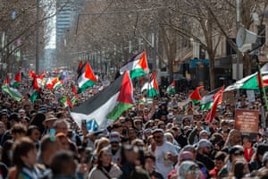 A large crowd of people march with Palestinian flags