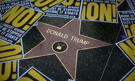 Hollywood Walk of Fame star for Donald Trump  framed in protest posters during a demonstration.