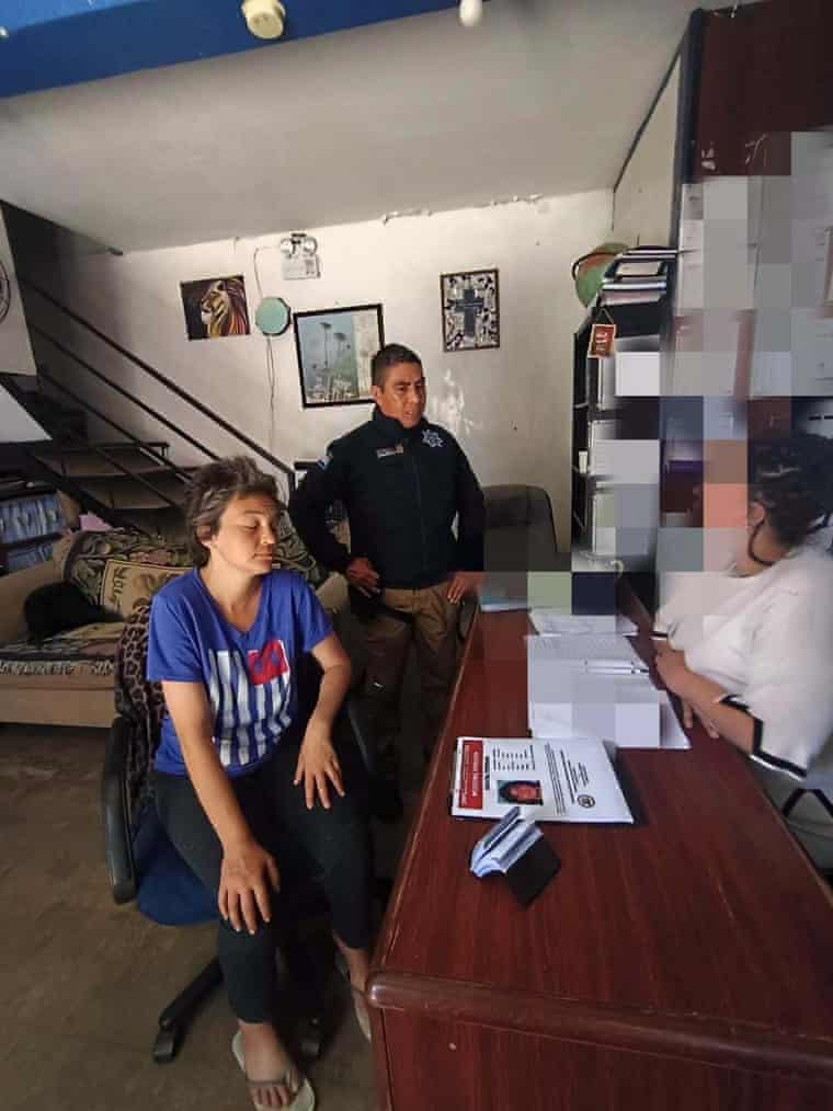 A woman is questioned by a police officer and another person at a desk