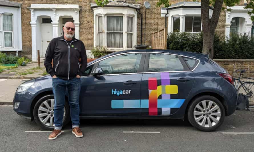 Man stands next to car with logo on it