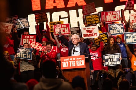 Man raises hand up at podium while people holding signs surround him