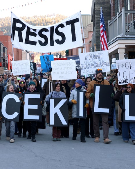group of people walk down street holding signs in protest