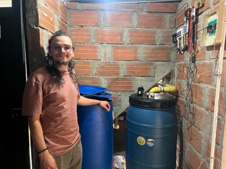 Róbinson Velásquez Cartagena standing in a small room next to two water butts.