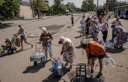 People on the street in Mykolaiv wait to fill empty containers with clean water brought by a tram.