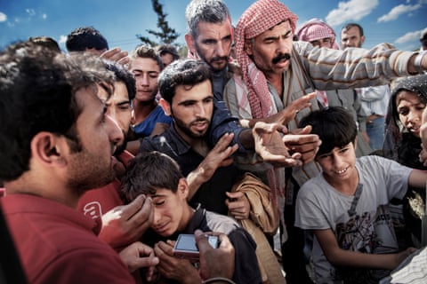 Syrian refugees wait around a truck where a volunteer is distributing water and soap in Akcakale on the border between Turkey and Syria