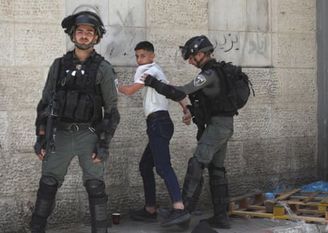 Israeli forces are seen detaining a young Palestinian as Jewish settlers parade in Bab al-Zawiya, Hebron, 25 April.