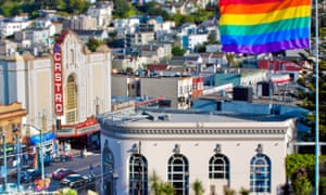 A rainbow flag flies on a mast above the gay-friendly Castro district of San Francisco, during a bright, sunny afternoon.