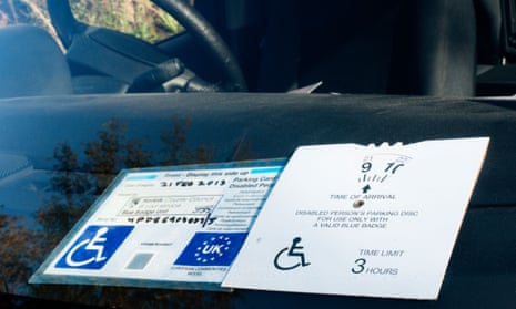 A blue badge parking permit on a car windscreen