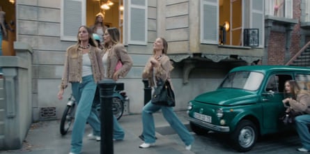 Still from video showing multiple Margot Robbies in a Parisian street, one kneeling next to a green vintage Fiat 500.