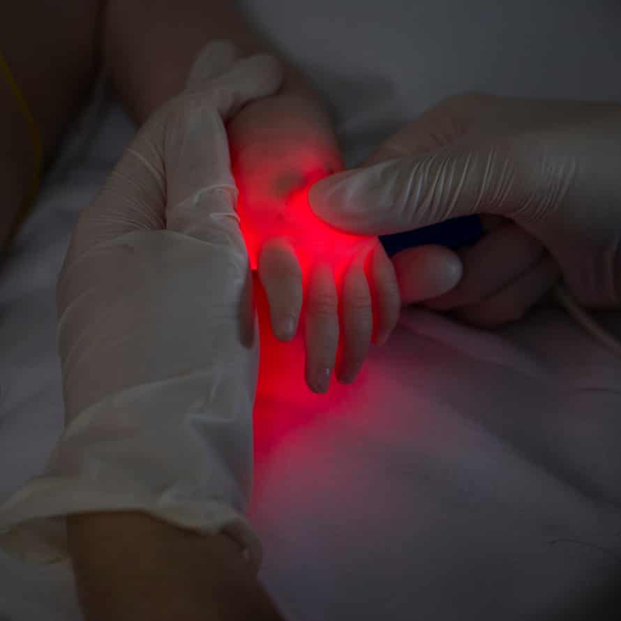 Dr Jana Kossaibati uses a torch to locate a vein in Marciee Barnes-Palmer’s hand