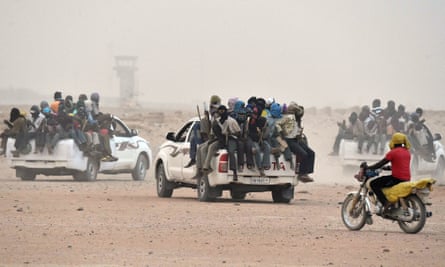 People sit on the back of pick-up trucks, as they leave the outskirts of Agadez, Niger, for Libya in 2015.
