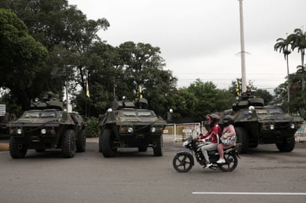 People ride on a motorbike next to military vehicles as Colombian soldiers patrol the border between Venezuela and Colombia