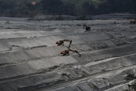 A huge open-cast mine with tiers of banked waste and diggers on three levels 