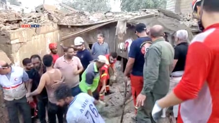Slightly blurry image of rescuers searching the rubble of a destroyed building