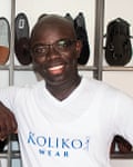 An African man poses in front of racks of shoes