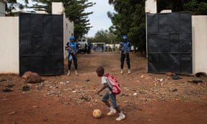 A boy plays football in front of two UN peacekeepers outside Mali’s Mamadou Konate stadium during an event organised to promote peace among young Malians.