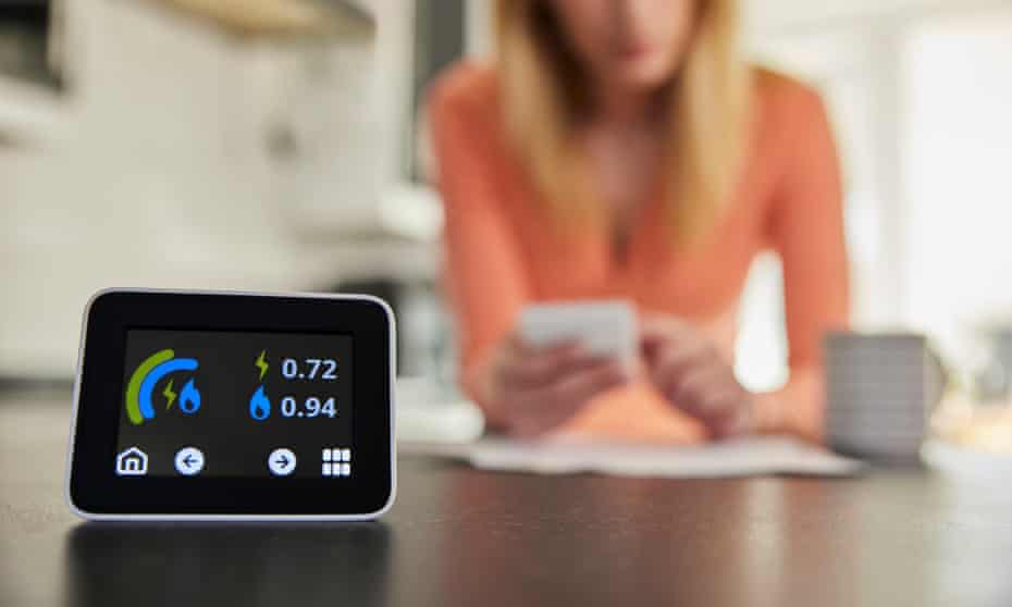 Close up of smart energy meter with woman looking at bills in the background