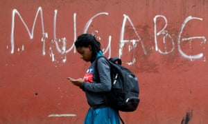 A woman in Harare walks past a wall with “Mugabe” scrawled on it