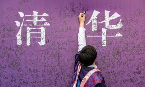 A graduate writes on a purple wall at a Chinese university degree commencement ceremony