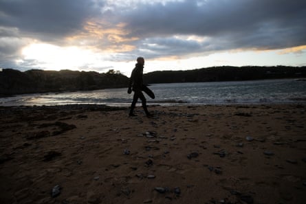 Freediver Callum Stewart walking across a beach in the first light of dawn.