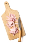 chopped ham with a knife on a wooden board