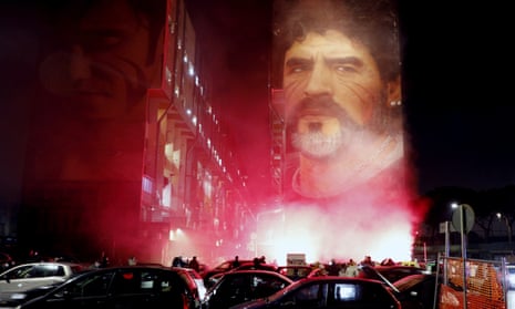 People light flares as they gather under a mural depicting football legend Diego Maradona, in Naples on Wednesday night.