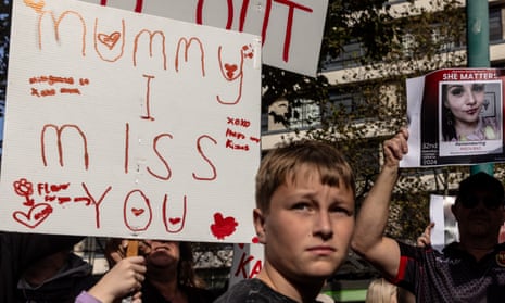 A boy looking sad in front of a children's placard that says 'Mummy I miss you'