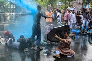 Protesters standing and lying in the street are fired on with a water cannon by police out of shot