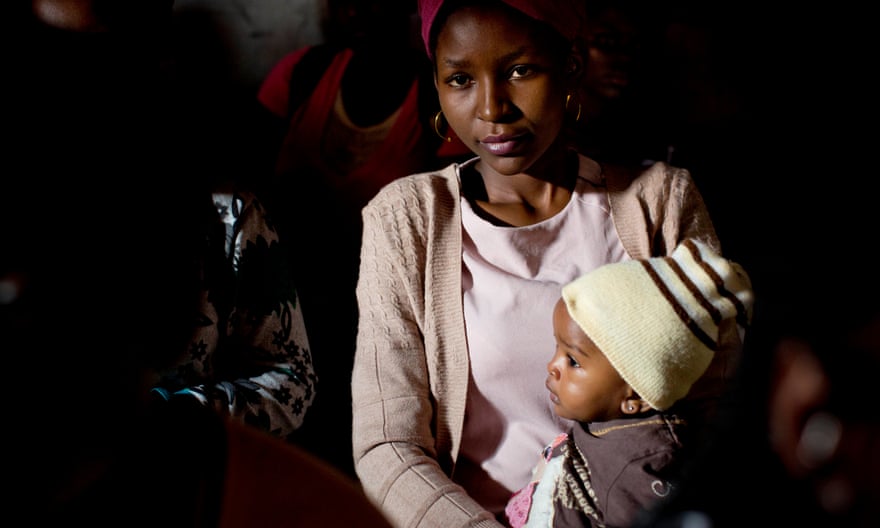 A young mother holds her baby at a community meeting in Kibera