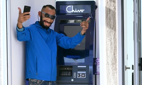 A man wearing a protective face mask with the image of the Salvadoran president, Nayib Bukele, poses for a picture at a bitcoin ATM in San Salvador, on Tuesday.