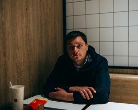 A man sitting in McDonald's with a soda cup and chips in front of him
