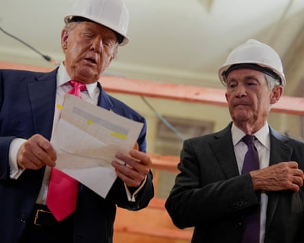 Donald Trump speaks and Jerome Powell wear hard hats during a visit to the Federal Reserve.