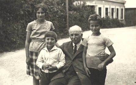 An old black-and-white photograph of a group posed on a track near a building: Malci’s stepdaughter, Chana Schickler, Julian’s father, Robert Borger, his great-grandfather Johann Borger and Mordechaj (Motti) Schickler.