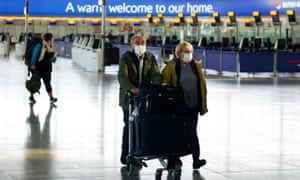 Passengers wearing face masks walk through arrivals at Heathrow