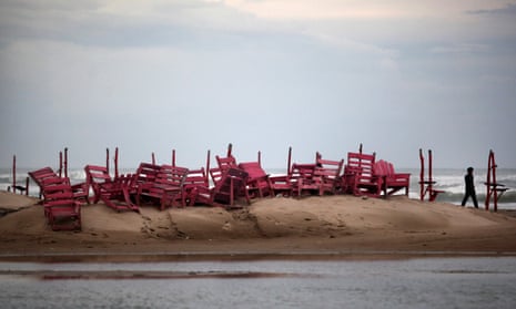 A man walks past tied up chairs at the Miramar beach as Hurricane Ingrid approaches the coast in Ciudad Madero, Mexico, in 2013.
