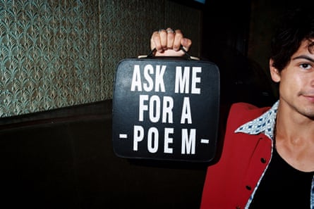 A person holds up a small case that has “Ask me for a poem” written on it
