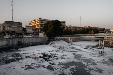 An industrial plant with water emptying from into a large basin with a scum lying on the water