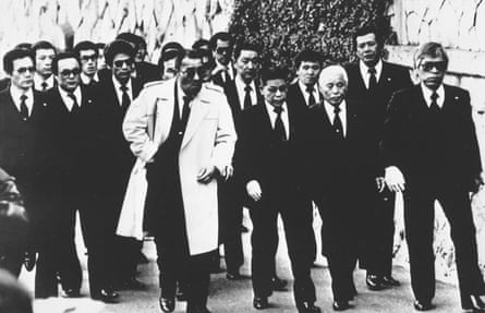 b&w shot showing suited and booted gangster-looking types taking a Reservoir Dogs style stroll
