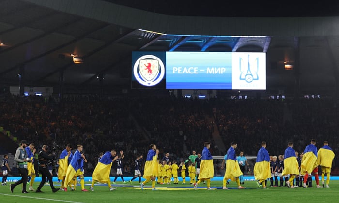 Teams take to the field with Ukraine players draped in their national flag.