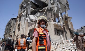 A member of civil defence teams stands in front of destroyed building in Rafah
