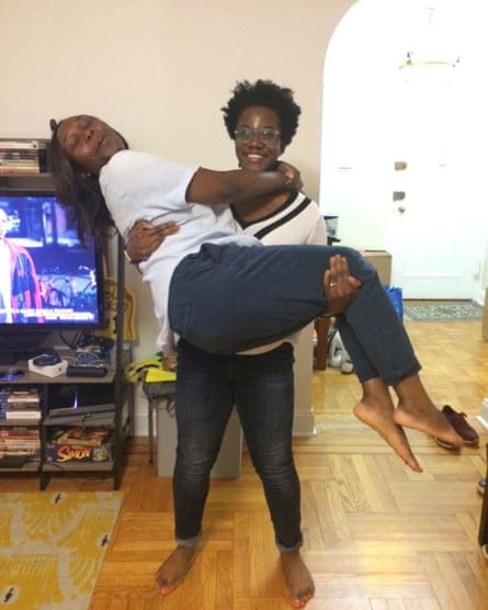 Two smiling black women, one lifting the other in her arms
